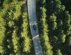 Top view of single gray car driving through forest in Zlatibor, Serbia. Aerial view from drone pov.